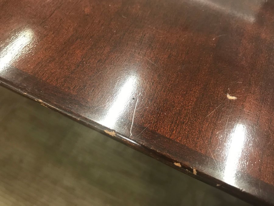 Close up image of a scratched and worn veneer conference table